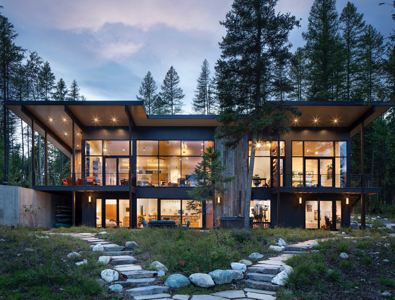 Contemporary architectural custom residence featuring stone masonry and copper detailing at sunset in Montana