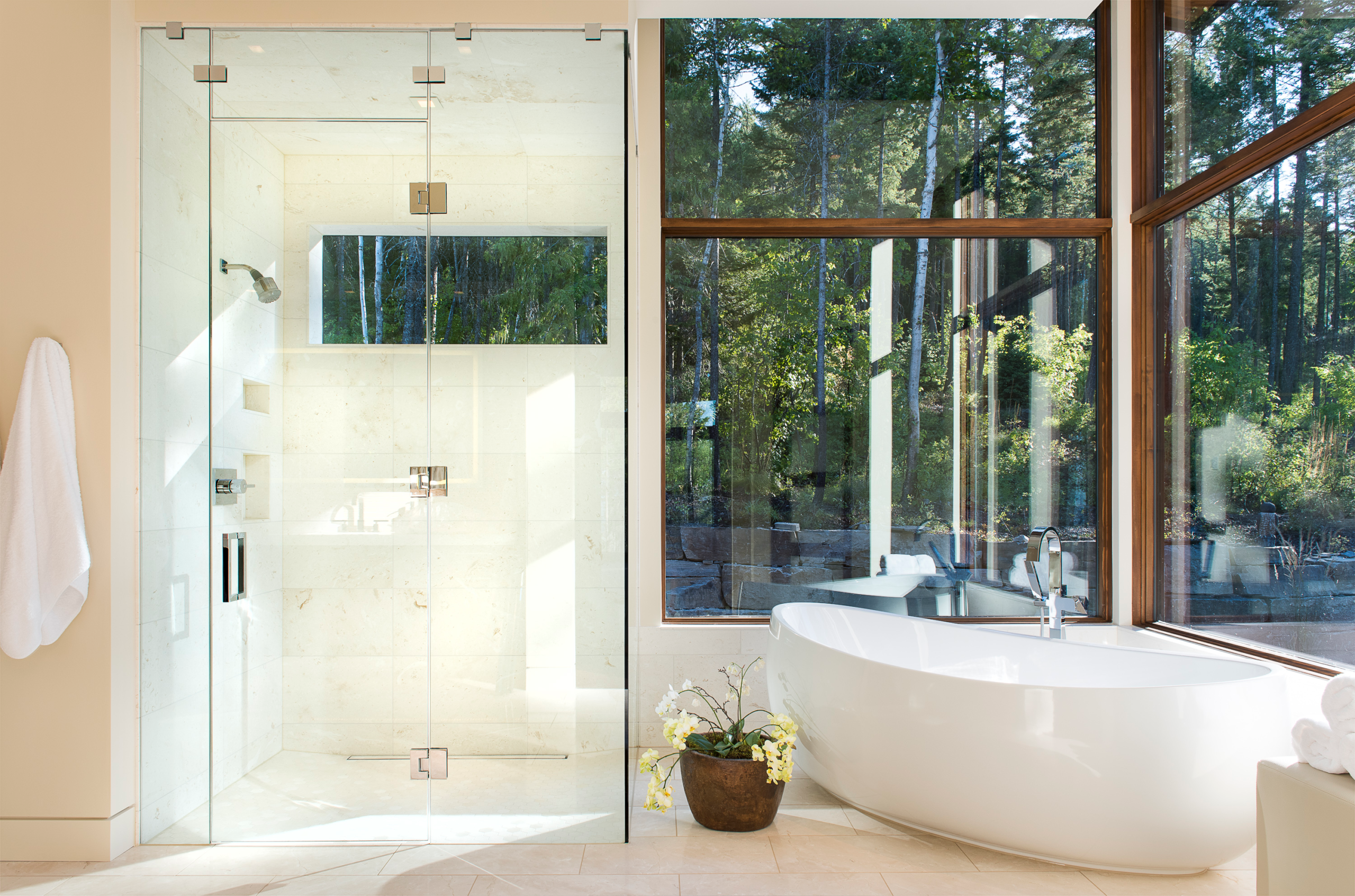 Freestanding stone resin soaking tub bordered by textured granite wall