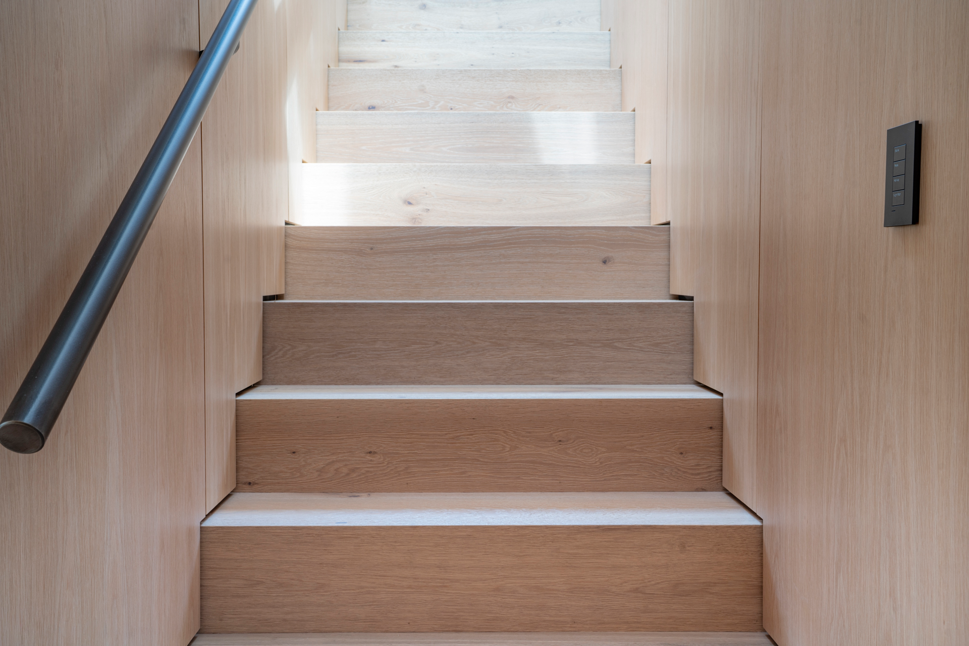 Open-tread blackened steel and white oak floating central staircase