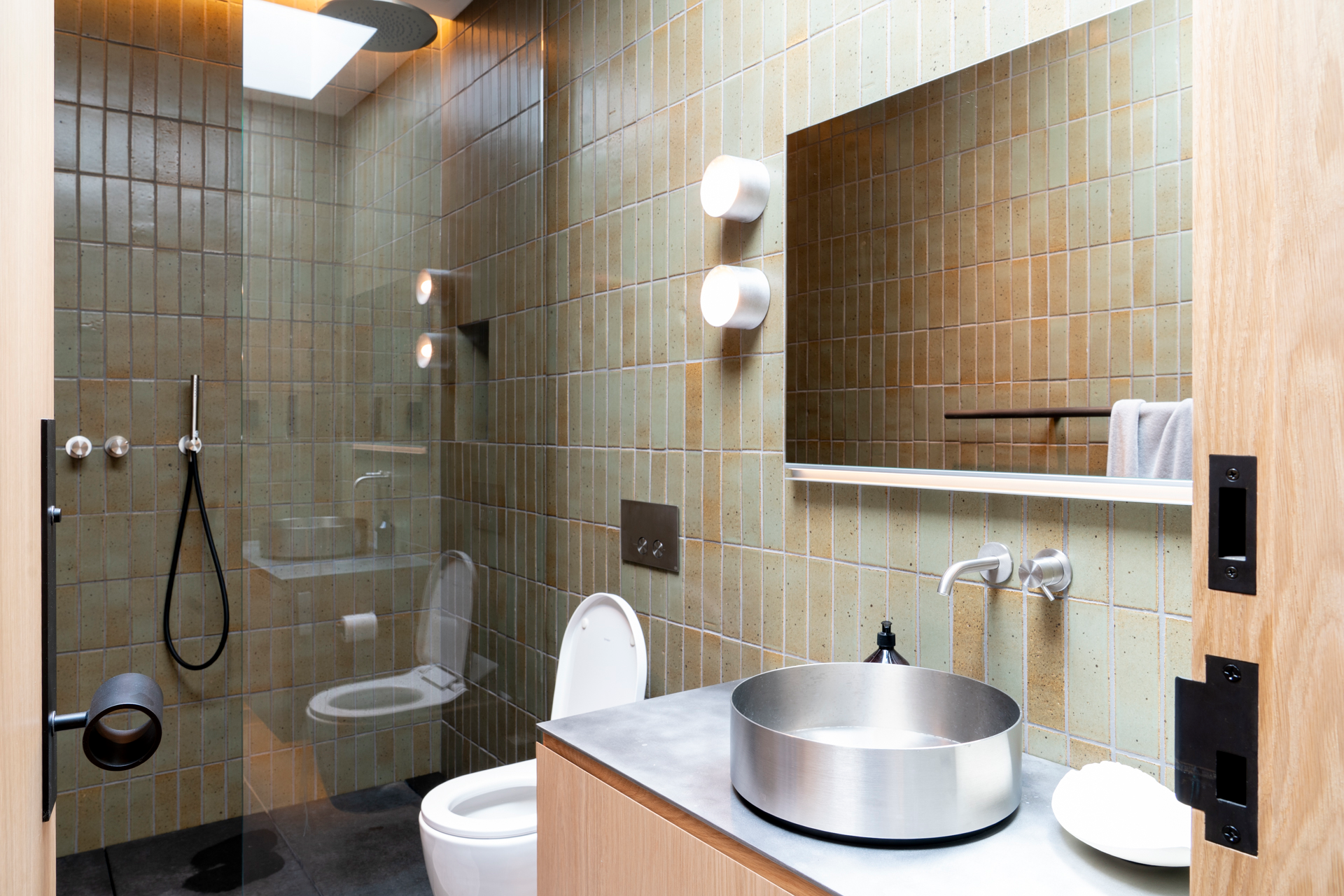 Freestanding stone resin soaking tub bordered by textured granite wall